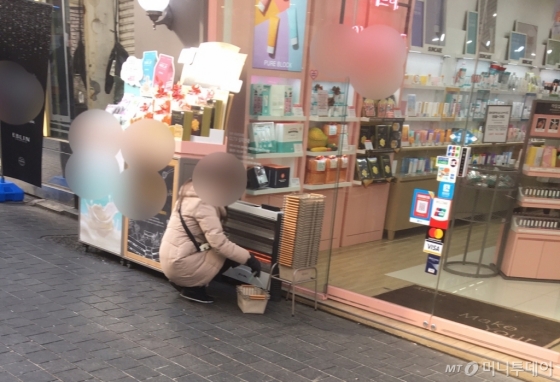 서울 중구 명동 소재 한 화장품 매장 앞에서 판촉 요원이 쭈그리고 앉아 정리를 하고 있다./사진=남형도 기자