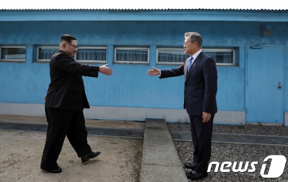 문재인 대통령(오른쪽)과 김정은 북한 국무위원장이 작년 4월27일 판문점 군사분계선 앞에서 만나 악수하기 위해 손을 내밀고 있다.. 2018.4.27/뉴스1 © News1 한국공동사진기자단