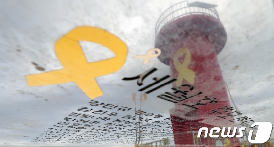 전남 진도 팽목항 방파제에 설치된 세월호 추모벤치 위에 새겨진 희생자들의 이름 위로 노란 리본이 그려진 빨간등대가 비춰지고 있다.  © News1