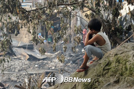 2015년 12월11일, 필리핀 마닐라에서 한 아이가 불에 탄 집을 바라보고 있다.