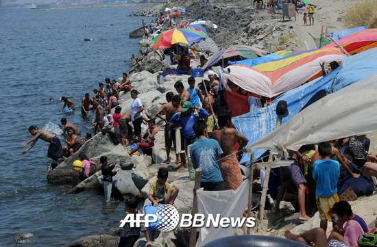 2015년4월4일, 필리핀 마닐라 슬럼가 거주민들이 마닐라 베이에 모여 더위를 달래고 있다. 당국은 '태풍 위험'이 있다며 수영을 금지했다. /AFPBBNews=뉴스1
