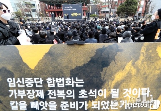 지난 9일 서울 종로 보신각 앞에서 열린 임신중단 전면 합법화 촉구 집회에서 한 참석자가 '낙태죄 위헌결정 촉구' 손피켓을 촬영하고 있다./사진=뉴스1