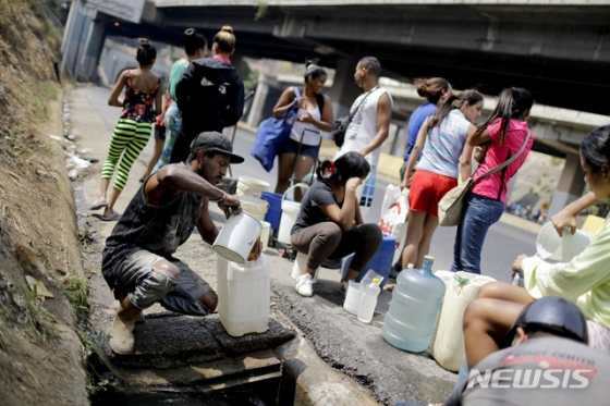【카라카스=AP/뉴시스】2일(현지시간) 베네수엘라 카라카스 주민들이 한 고속도로 인근의 도랑에서 물을 길어 올리고 있다. 2019.04.03. / 사진=민경찬