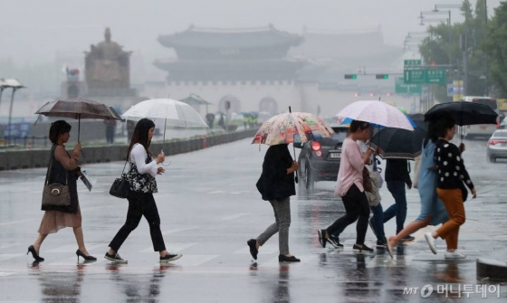 전국적으로 오락가락 빗방울이 떨어진 19일 오후 서울 광화문 인근을 지나는 시민들이 우산을 쓰고 발걸음을 재촉하고 있다./사진=이동훈 기자