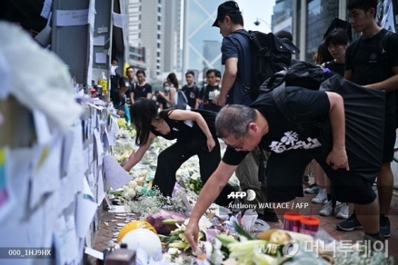 홍콩 시민들이 16일 '범죄인 인도 법안' 반대 시위에 참석하기 앞서 전날 오후 늦게 고공 시위 중 사망한 한 시민을 추모하기 위해 꽃을 놓고 있다. / 사진=AFP 
