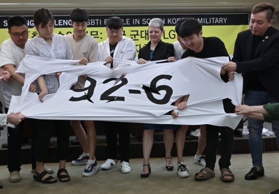 11일 서울 중구 프레스센터에서 국제앰네스티 한국지부 활동가들이 동성 간 성관계를 금지하는 군형법 제92조 6항을 폐지해야 한다는 의미에서 '92-6'이라고 적힌 현수막을 찢는 퍼포먼스를 하고 있다. /사진=AFP
