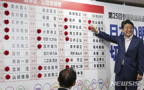 【도쿄=AP/뉴시스】아베 신조 일본 총리가 21일 일본 도쿄 자민당 선거상황실에서 참의원 선거에서 승리한 여당 후보 당선자의 이름 옆에 당선 축하 표시 장식을 달고 있다./사진=뉴시스