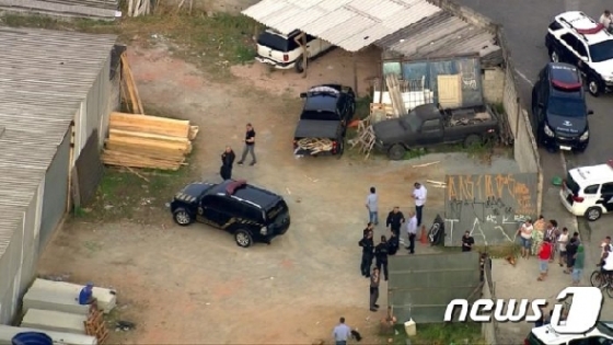 브라질 상파울루 한 시골마을에 강도 일당이 버린 차량을 경찰이 조사 중이다. <현지 언론 구아룰류스신문 갈무리>© 뉴스1