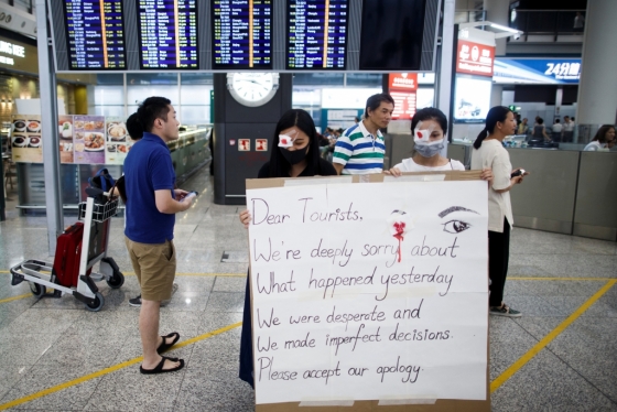 14일 홍콩국제공항에서 시위대에 참가한 시민들이 전날 벌어진 난투극에 대해 사과하는 피켓을 들고 있다. /사진=로이터