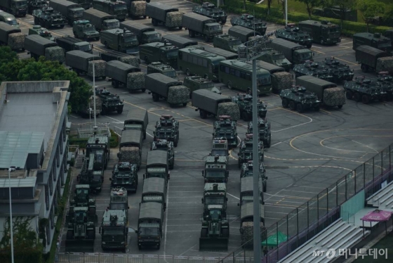 【선전(중국 광둥성)=AP/뉴시스】홍콩과 인접한 중국 광둥성 선전의 스포츠 스타디움에서 16일(현지시간) 중국 인민해방군 소속 무장한 차량과 군용 트럭들이 늘어서 있다.   중국 정부와 매체들이 홍콩 시위를 ‘테러’와 ‘색깔 혁명’ 등으로 규정하고 홍콩 건너편 선전에 무장병력을 집결시키면서 홍콩 시위대에 대한 무력개입이 임박한 게 아니냐는 관측이 나오고 있다.   홍콩 시위대는 이번 주말 30만 명이 집결하는 시위를 계획하고 있어 중국의 무력개입 여부를 가르는 분수령이 될 것으로 전망되고 있다. 201.08.16.