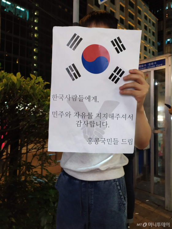 지난 23일(현지시간) 밤 홍콩 도심서 열린 '인간 띠' 시위에 참가한 한 남성이 태극기와 시위를 지지해준 한국인에게 감사하다는 내용의 문구가 새겨진 종이를 들고 있다. /사진=유희석 기자