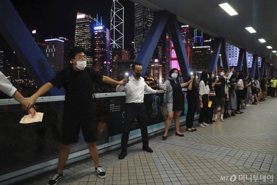 【홍콩=AP/뉴시스】23일(현지시간) 홍콩 거리에서 송환법 반대 시위대가 손을 잡고 한 줄로 서서 인간 띠 시위를 벌이고 있다.    시위대는 1989년 8월 23일 발트 3국의 국민이 손을 맞잡고 670km에 이르는 ‘발트의 길’을 만들어 소련에 저항한 역사적 사건에 영감을 받아 시내와 항구 등에서 60km에 달하는 인간 띠를 형성해 이른바 '홍콩의 길' 시위를 벌였다. 2019.08.24.