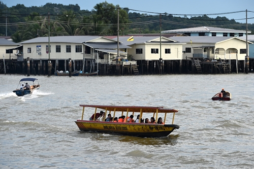 관광객들이 보트를 타고 캄퐁 아에르(Kampong Ayer·브루나이 강 위에 지어진 수상 가옥촌) 근처를 구경하고 있다. /사진=AFP