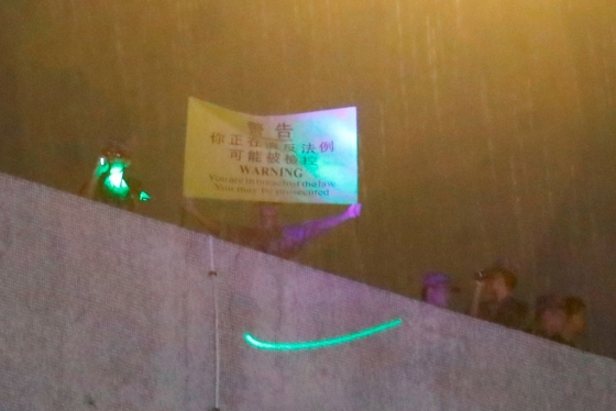 중국 인민해방군이 막사 내에서 노란 깃발을 들고 시위대에 경고를 보내고 있다. 깃발에는 "당신은 법을 어기고 있으며 기소될 수 있다"고 번체자와 영어로 쓰여 있다. /사진=로이터