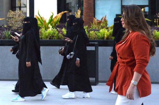 한 외국인 여성이 아바야를 입은 사우디 여성들 옆을 지나가고 있다. /사진=AFP