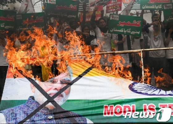 지난달 27일(현지시간) 파키스탄 동북부 라호르에서 '카슈미르 청년 포럼' 활동가들이 나렌드라 모디 인도 총리와 인도 국기가 그려진 현수막을 불태우고 있다.  © AFP=뉴스1