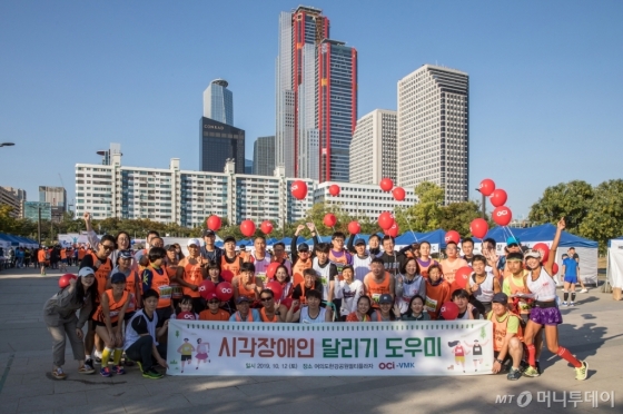 10월 12일 서울 여의도 한강공원에서 열린 시각장애인 마라톤 대회에서 참가들과 봉사자들이 단체사진을 찍고 있다./사진제공=OCI