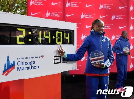 13일(현지시간) 2019 시카고 마라톤 대회에서 2시간14분4초 기록으로 세계기록을 다시 쓴 브리지드 코스게이(케냐)가 기록 전광판 앞에서 포즈를 취하고 있다. © AFP=뉴스1