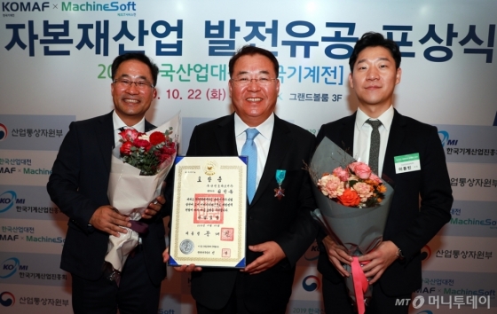 두산인프라코어 김인동 전무(가운데)가 10월 22일 킨텍스에서 열린 ‘2019 한국산업대전’ 개막식에서 한국 자본재 산업 발전에 기여한 공로로 정부 산업포장을 수상했다./사진제공=두산인프라코어