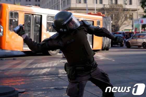 (산티아고 AFP=뉴스1) 우동명 기자 = 20일 (현지시간) 산티아고에서 지하철 요금 인상으로 촉발된 칠레 반정부 시위대를 향해 경찰이 최루탄을 던지고 있다.   © AFP=뉴스1  