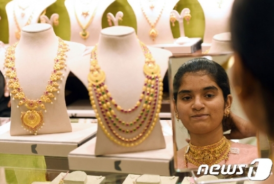 지난 5월7일(현지시간) 인도 샤나이에 있는 한 금은방에서 인도 여성이 금목걸이를 착용해보고 있다. © AFP=뉴스1