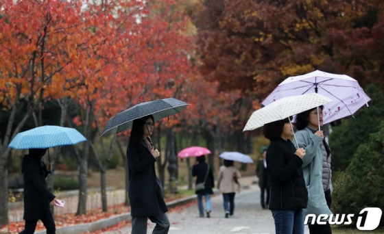 가을비가 내린 13일 오후 서울 여의도공원에서 시민들이 우산을 든 채 발걸음을 재촉하고 있다. / 사진 = 뉴스 1