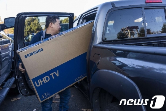 추수감사절 연휴에 한 쇼핑객이 삼성전자의 TV를 사서 자신의 차에 넣고 있다. © AFP=뉴스1
