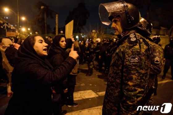지난 11일(현지시간) 이란 수도 테헤란 소재 아미르카비르 공대 앞에서 진행된 '우크라이나 여객기 격추사건' 희생자 추모 집회에 참석한 한 여성이 집회 통제에 나선 경찰관에게 항의하고 있다. © AFP=뉴스1