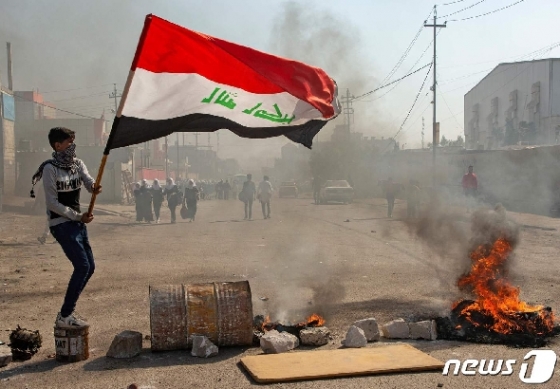 20일(현지시간) 이라크 남부 바스라에서 반정부 시위자가 이라크 국기를 흔들고 있다. © AFP=뉴스1
