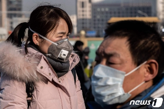 21일(현지시간) 신종 코로나바이러스인 우한 폐렴의 감염을 피하기 위해 시민들이 마스크를 쓴 채 베이징 지하철 밖 경찰서 앞을 지나고 있다. © AFP=뉴스1 © News1 우동명 기자