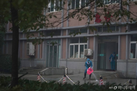 [우한=AP/뉴시스] 신종 코로나바이러스가 원인균으로 알려진 폐렴에 감염된 환자들이 수용돼 있는 중국 우한치료센터(Wuhan Medical Treatment Center)의 22일 외부 모습. 보호복을 입은 사람이 물을 끼얹고 있다. 2020.01.23