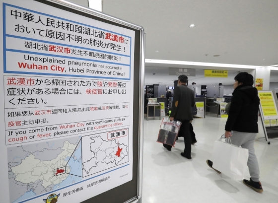 일본 나리타 공항에서 승객들이 신종 코로나바이러스와 관련된 표지판을 지나가고 있다. /사진=AFP