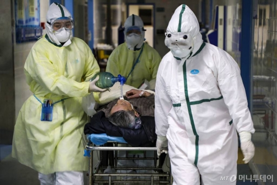 [우한=AP/뉴시스] 중국 후베이성 우한의 한 병원에서 6일 보호복을 입은 의료진이 코로나 19 환자를 격리병동으로 옮기고 있다. 2020.02.13
