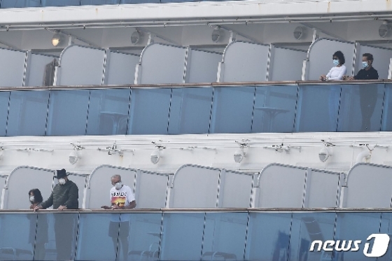 14일 신종 코로나바이러스 감염자 급증 속 요코하마항에 강제 격리된 채 정박해 있는 다이아몬드 프린세스호의 승객들이 마스크를 쓰고 밖을 내다보고 있다. © AFP=뉴스1 © News1 우동명 기자