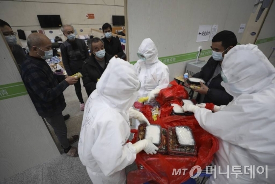 [우한=AP/뉴시스]21일(현지시간) 중국 후베이성 우한의 타즈후 체육센터에 마련된 임시 병원에서 방호복을 입은 관계자들이 신종 코로나바이러스 감염증(코로나19) 환자들에게 음식을 나눠주고 있다. 중국 국가위생건강위원회는 22일 오전 0시 기준 코로나19 사망자가 총 2345명, 확진자는 총 7만6288명이라고 공식 발표했다. 2020.02.22.