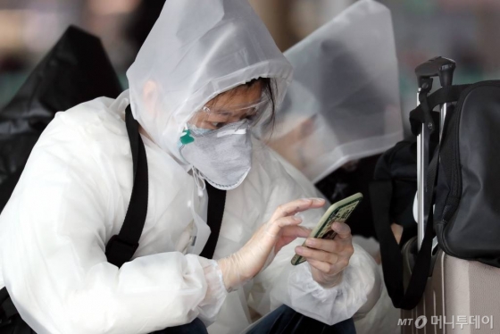 코로나19가 빠르게 확산하는 가운데 26일 인천국제공항에서 한 여행객이 보호장비를 착용하고 휴대전화를 만지는 모습./사진=이기범기자