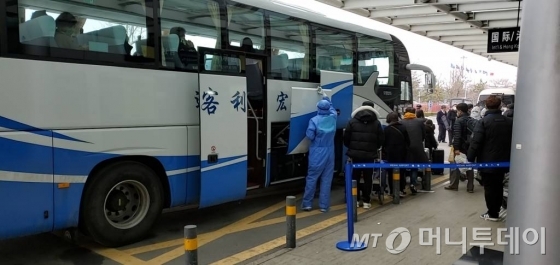 [서울=뉴시스] 박민석 기자=중국 산둥성 웨이하이국제공항에서 25일 방역요원들이 제주항공편으로 입국한 승객들을 버스에 태우고 있다. (사진=독자 제공) 2020.02.25.    photo@newsis.com
