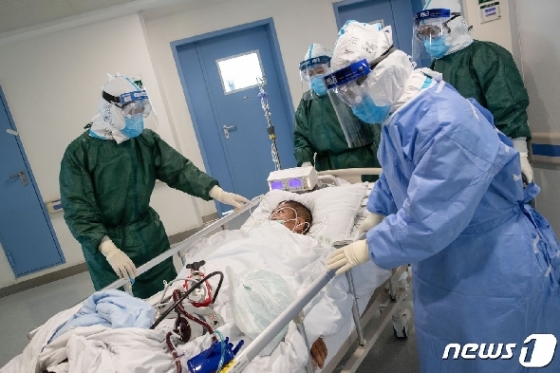 지난달 22일 코로나 19의 발원지인 후베이성 우한의 병원에서 의료진들이 감염환자를 옮기고 있다. © AFP=뉴스1 © News1 우동명 기자