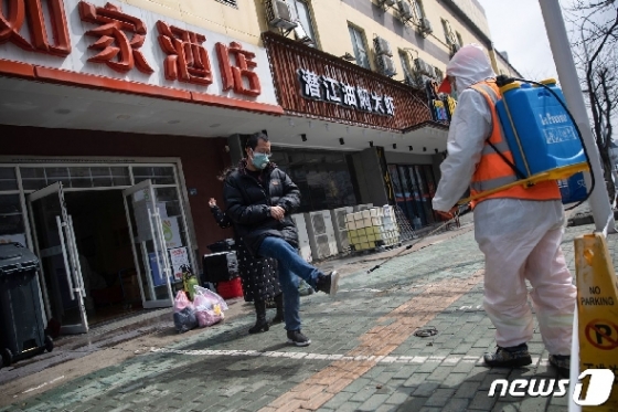 1일(현지시간) 코로나19에 감염됐다 완치된 한 남성이 중국 후베이성 우한시의 한 호텔 앞에서 자원봉사자들로부터 소독을 받고 있다. © AFP=뉴스1