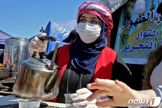 4일 이라크 바그다드 타흐리르 광장의 한 여성이 마스크를 쓴 채 컵에 차를 따르고 있다. © AFP=뉴스1