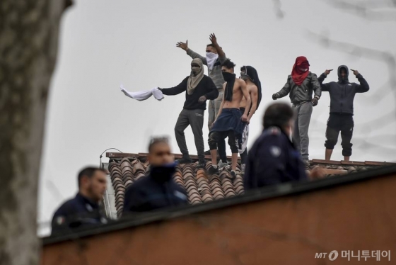 [밀라노=AP/뉴시스] 코로나 19로 전국에 이동금지령이 내려지자 9일(현지시간) 이탈리아 밀라노 산비토레 교도소 수감자들이 면회 재개를 요구하며 폭동을 일으켜 지붕 위에 올라가 시위를 벌이고 있다. 2020.03.10