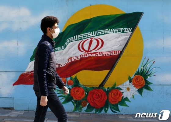 지난 4일(현지시간) 이란 수도 테헤란에서 한 남성이 이란 국기가 그려진 벽화 앞을 지나고 있다. © AFP=뉴스1