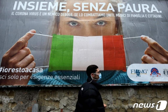 22일 이탈리아 나폴리 거리에서 한 남성이 코로나-19의 확산에 맞서기 위해 이탈리아 정부가 제작한 대형 광고판 앞을 지나가고 있다.  /사진제공=뉴스1