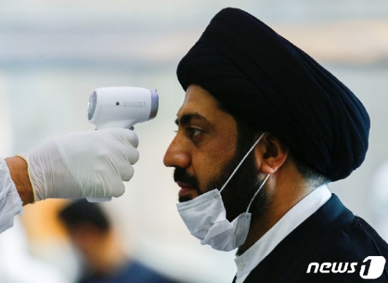 이란 보건요원이 한 이슬람 성직자의 열을 재고 있다. © 로이터=뉴스1