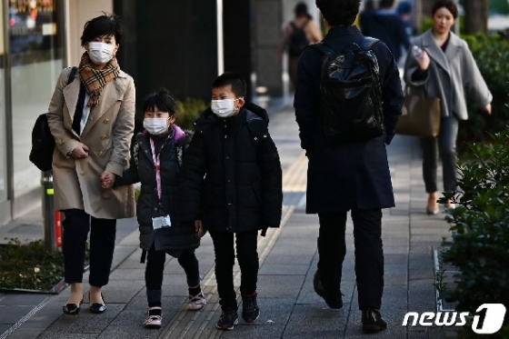 지난 6일 마스크를 착용한 어머니(왼쪽)와 아들·딸 등 가족이 일본 도쿄 시내를 걸어가고 있다.  © AFP=뉴스1