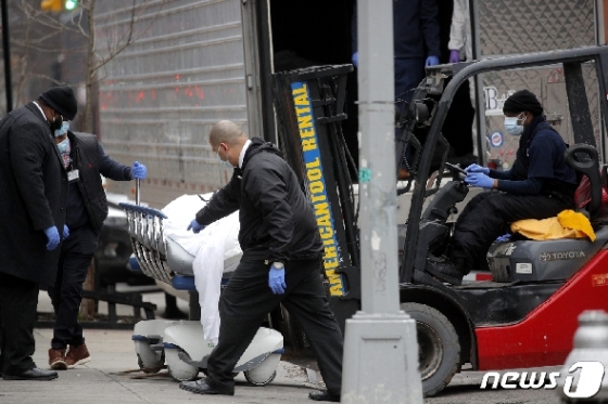 30일 미국 뉴욕주 브루클린 병원 앞에서 직원들이 코로나19 사망자의 시신을 지게차에 싣기 위해 운반하고 있다. © 로이터=뉴스1 © News1 유새슬 기자