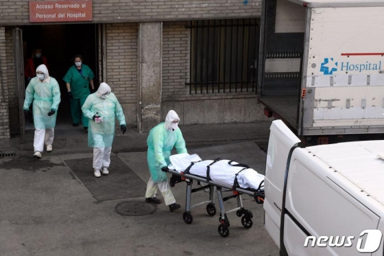 (마드리드 AFP=뉴스1) 우동명 기자 = 25일 (현지시간) 스페인 마드리드의 그레고리오 마라논 병원에서 의료진들이 숨진 코로나19 환자를 이송하고 있다.  ⓒ AFP=뉴스1