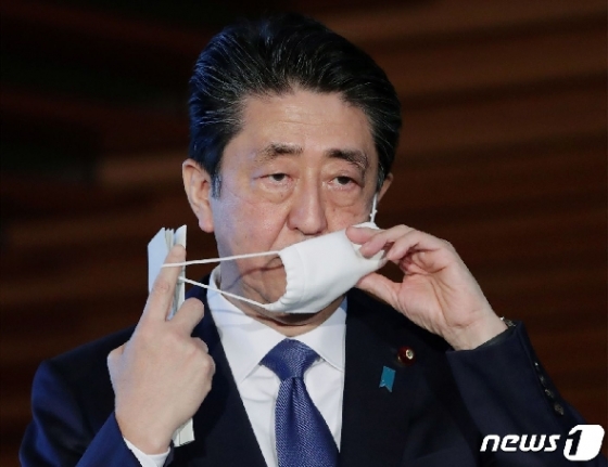 아베 신조 일본 총리가 6일 총리 관저에서 기자회견을 실시하기 전 마스크를 벗고 있다.  ⓒAFP=뉴스1
