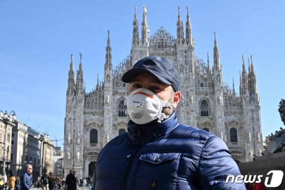 이탈리아 북부 밀라노에서 코로나19에 대한 우려로 마스크를 착용한 한 시민이 두오모 대성당 앞을 지나가고 있다./ AFP=뉴스1