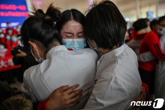 지난 8일 코로나19 진원지로 76일만에 봉쇄령이 해제된 후베이성 우한 텐허 공항에서 지린성과 우한의 의료진이 포옹을 하며 울고 있다. © AFP=뉴스1 © News1 우동명 기자